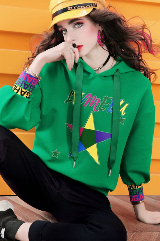 Person wearing a green hoodie with colorful designs against a yellow background